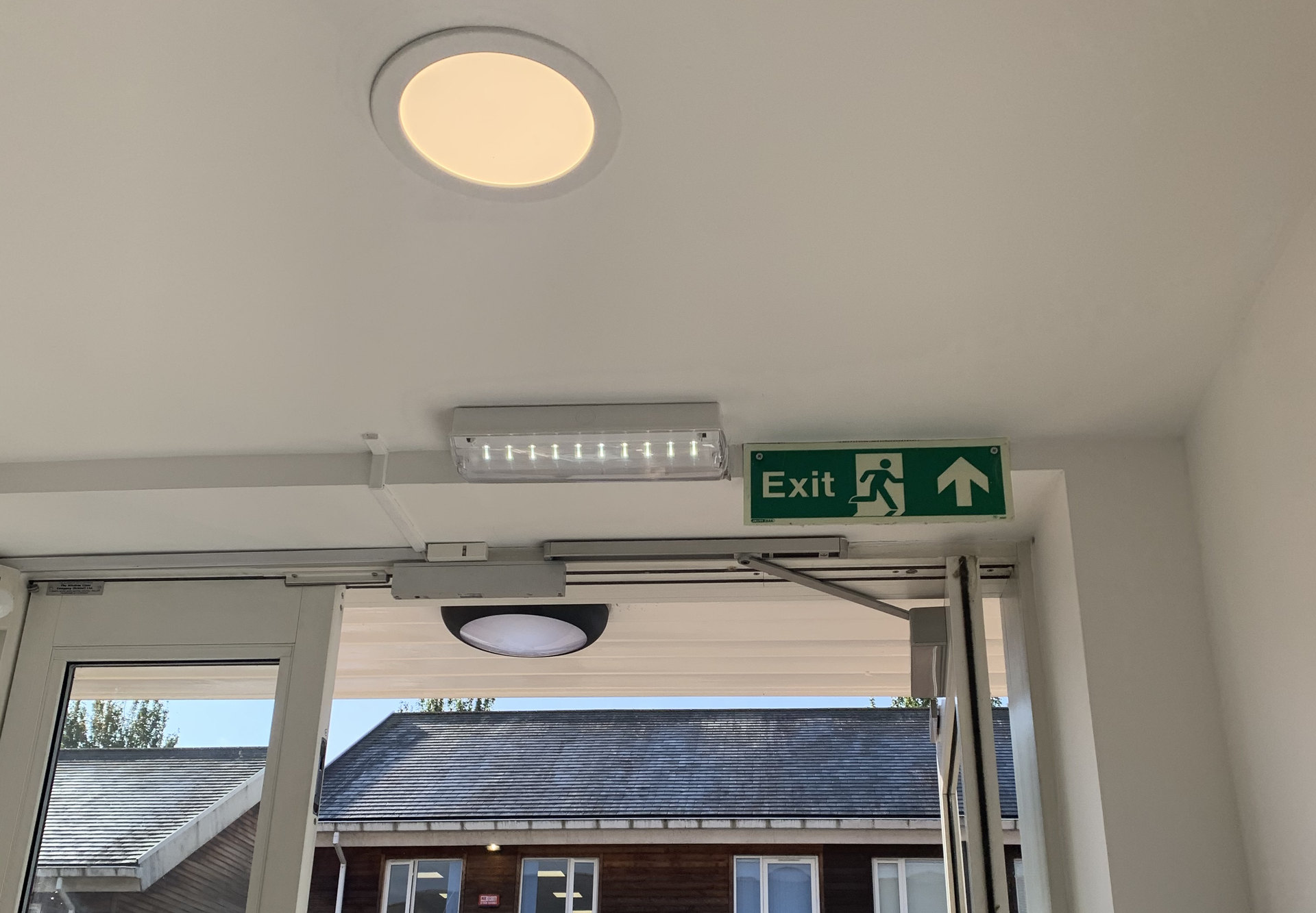 Emergency light and exit sign above a commercial entrance