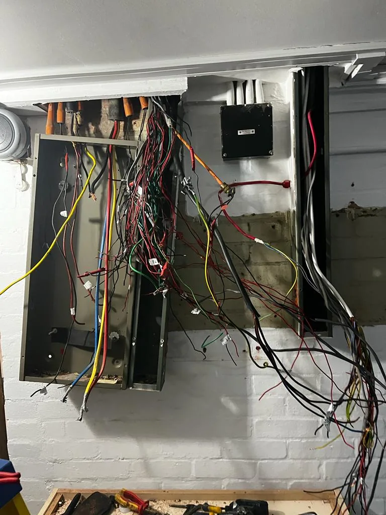Exposed wiring inside an open electrical panel during work